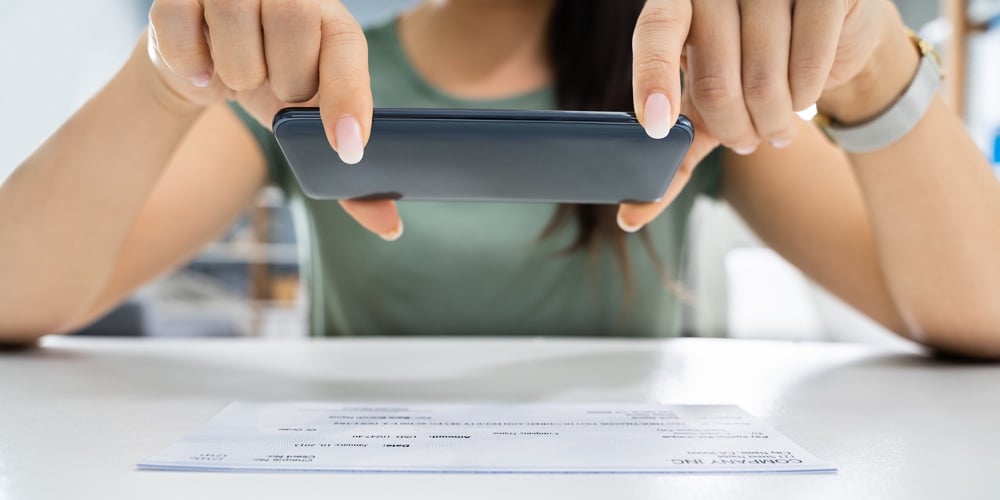 bigstock-Woman-Taking-Photo-Of-Cheque-T-329852467